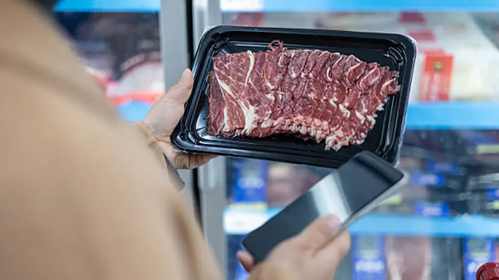 woman selects frozen food from the refrigerated display case in a supermarket