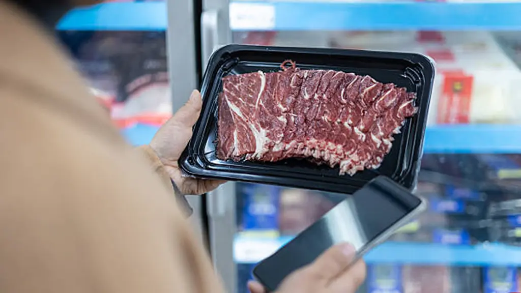 woman selects frozen food from the refrigerated display case in a supermarket
