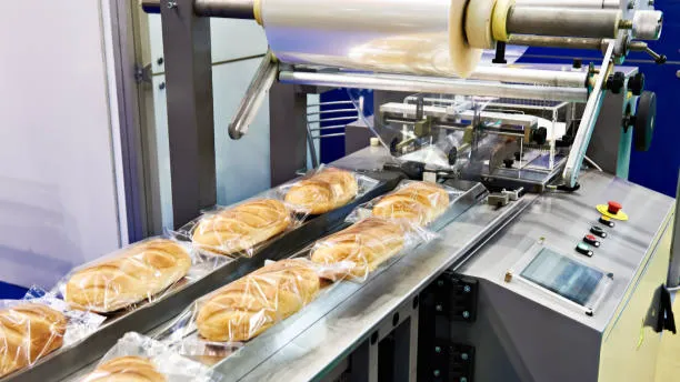 Loaves of bread moving through an automatic packaging machine on a conveyor belt