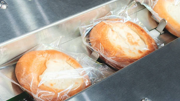 Individually wrapped pastries on chain conveyor after horizontal flow packing and sealing